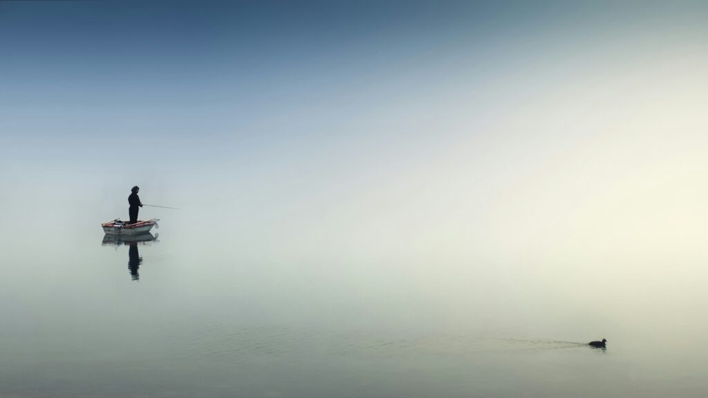 Solitary fisherman on a calm, still lake, reflecting a regulated nervous system