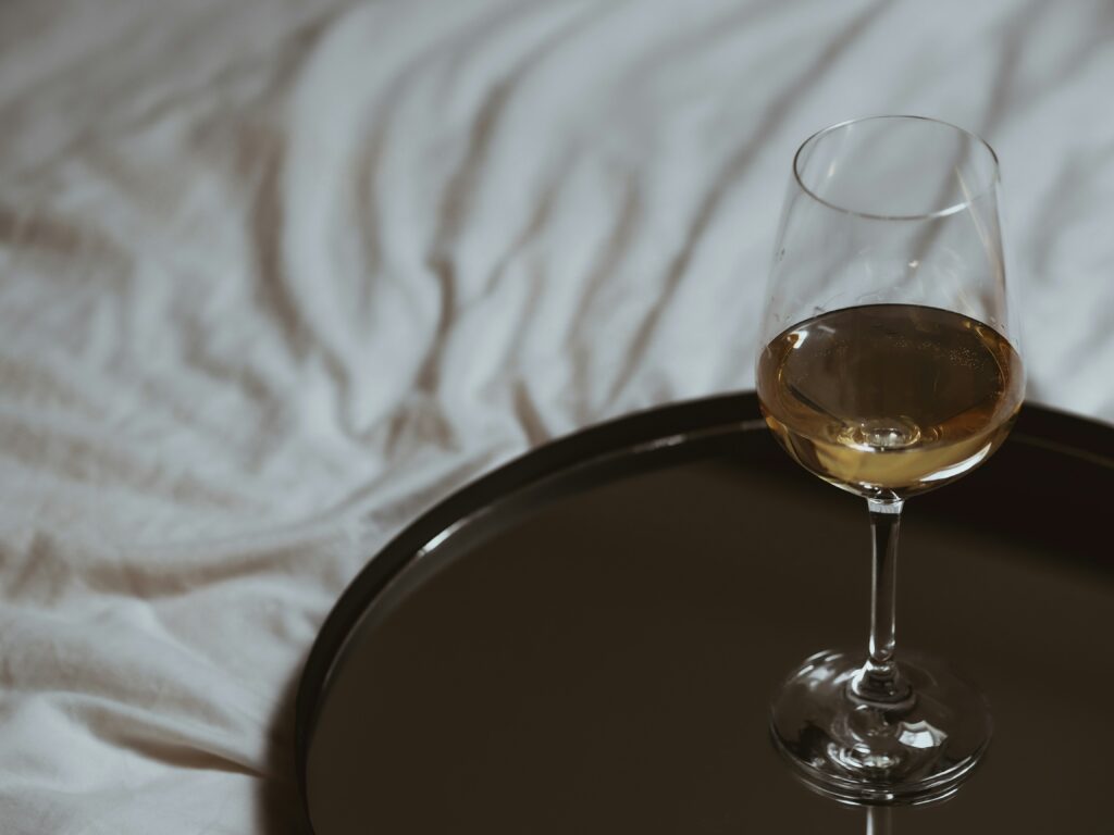 Alcohol and sleep: a drink in a glass on a bed
