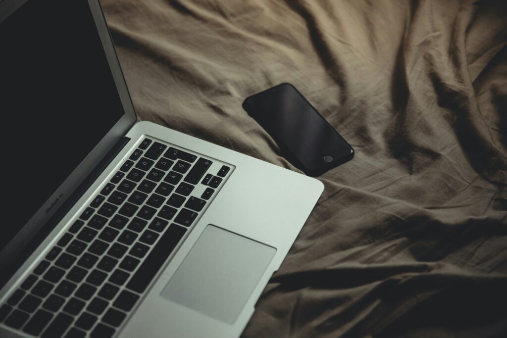 Screens before bed: a laptop glowing on a pillow in a dark bedroom