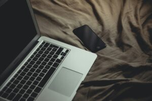 Screens before bed: a laptop glowing on a pillow in a dark bedroom