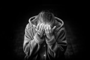 Person seated with head hung in their hands, showing the weight of PTSD